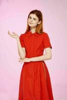 skön kvinna i röd klänning hand gester lyx rosa bakgrund foto
