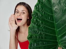 glad kvinna bred öppen mun grön blad röd baddräkt närbild foto