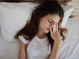 kvinna liggande i säng med stängd ögon missnöjd ansiktsbehandling uttryck foto
