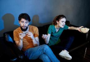 en man med en mobil telefon och en Söt kvinna tittar på TV inomhus i de kväll foto