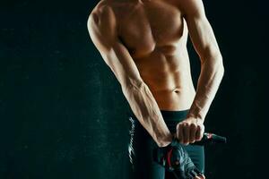 atletisk män med en taggad kropp träna Framställ mörk bakgrund foto