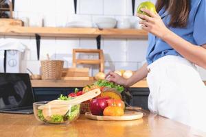 diet, ljushyad ung asiatisk kvinna i en blå skjorta äter vegetabiliska sallad och äpplen som en friska diet, välja för skräp mat. kvinna dietist förlorande vikt. friska äter begrepp. foto