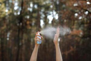 kvinnors händer som applicerar alkoholspray eller anti-bakteriespray utomhus för att förhindra spridning av bakterier, bakterier och virus, karantentid, fokusera på närbildshänder. coronavirus. kopiera utrymme. foto