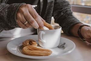 närbild av en man äter en typisk spanska frukost och churros med choklad foto