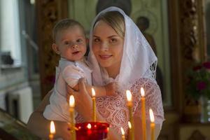 ortodox dop. mor och barn i en kyrka förbi levande ljus. kvinna med en bebis i de tempel. foto