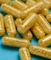 transparent medicinsk kapslar med gul granulat inuti på en blå bakgrund, tabletter för behandling, vitaminer foto
