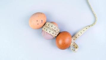 kyckling ägg insvept i mätning tejp på ägg på vit bakgrund. friska mat och diet begrepp. foto