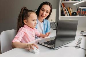 mamma som hjälper dottern med virtuell utbildning foto