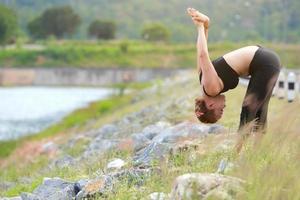 ung flicka håller på med yoga kondition övning morgon- soluppgång utomhus- i de äng skön bergen landskap. meditation och koppla av. foto