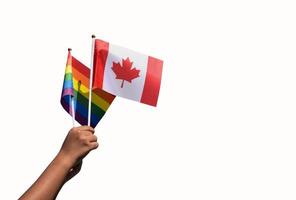 isolerat kanada flagga och regnbåge flagga innehav i hand klippning vägar', begrepp för fira av HBTQ människor i kanada i stolthet månad, juni. foto