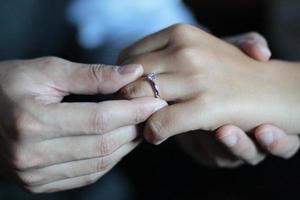 brudgum sätter de ringa på de brudens hand i i thai bröllop ceremoni traditionell. foto