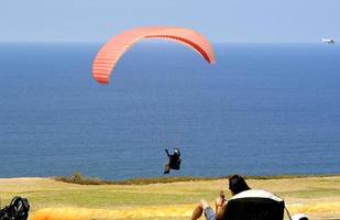 i san diego, Kalifornien, från de klippor av svarts strand, en paraglider lanserar in i de vindby vind. foto
