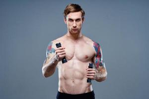 naken man håller på med sporter på grå bakgrund och hantel tatuering beskurna se foto