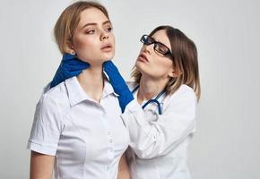 en kvinna läkare i en medicinsk klänning och blå handskar undersöker de patientens ansikte foto