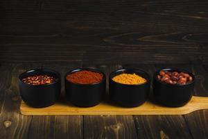 kryddor och örter i keramisk skålar med stå på trä- tabell foto