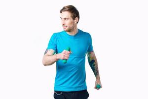 sporter man i en blå t-shirt med hantlar i hans händer kondition övningar tatuering foto
