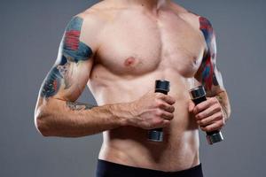 manlig idrottare med en tatuering på hans ärm naken torso uppblåst muskler hantlar kondition foto