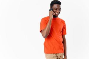 ung afrikansk man med mobil telefon nära öra på ljus bakgrund foto