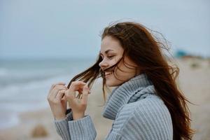kvinna i en Tröja flygande hår förbi de hav turism oförändrad foto