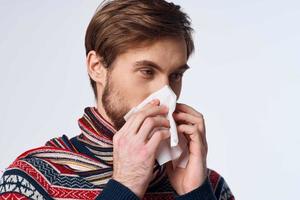 emotionell man avtorkning hans näsa med en näsduk infektion virus ljus bakgrund foto