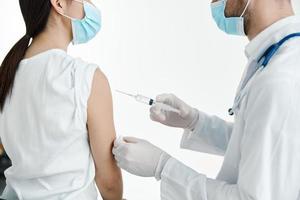 läkare i en vit täcka injicering en kvinnas axel vaccination handskar foto