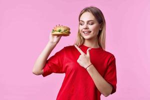 kvinna i röd t-shirt snabb mat mellanmål rosa bakgrund foto