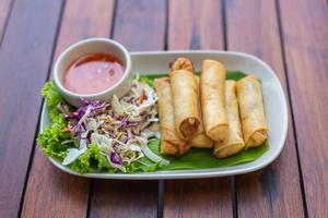 djup friterad vår rullar por brygga tod eller friterad vår rullar thai vår rulla eras med grönsaker och doppning sås på de trä- tabell snacks den där är populär med thai och kinesisk människor. foto