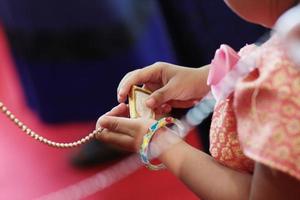 kvinna hand innehav guld halsband i thai engagemang ceremoni.thai bröllop kultur tradition. foto