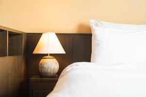 vit bekväm kudde på sängen med ljuslampa foto
