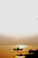 kväll gyllene solnedgång tid, en fiskare fiske på de havet på en båt. foto