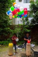 bangladesh september 08, 2020 två ballong säljare är injicering gas in i några färgrik ballonger genom två gas cylindrar på dhaka, bangladesh. foto