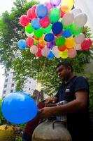 bangladesh september 08, 2020 två ballong säljare är injicering gas in i några färgrik ballonger genom två gas cylindrar på dhaka, bangladesh. foto