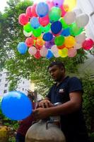 bangladesh september 08, 2020 två ballong säljare är injicering gas in i några färgrik ballonger genom två gas cylindrar på dhaka, bangladesh. foto