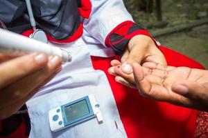 kvinna kontroll socker nivå med glukometer använder sig av en blod prov på narsingdi, bangladesh. lära sig till använda sig av en glukometer. begrepp av diabetes behandling. foto