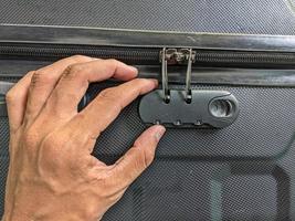 man händer upplåsning en koda hänglås på en resväska foto