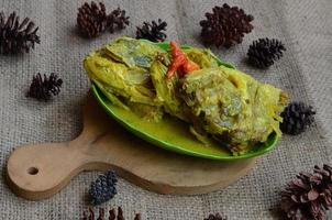 gulai kepala kakap eller snapper fisk huvud, kokta i curry krydda, den smakar kryddad, sur och välsmakande. traditionell padang kök, väst sumatra, Indonesien. foto
