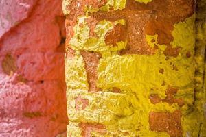 röd, orange, gul och blå Färg kombination gammal texturerad skada vägg med färgrik tegelstenar. foto