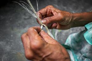 ett gammal ålder kvinna är framställning på hans mager händer en rep från de banan träd fiber på madhupur, tangail, bangladesh. foto