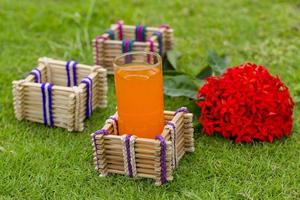 bambu pinnar glas hållare med en glas av orange juice på gräs bakgrund. foto