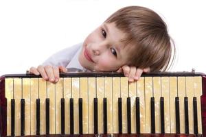 barn med en musikalisk instrument. elementärt ålder pojke med ett dragspel. foto