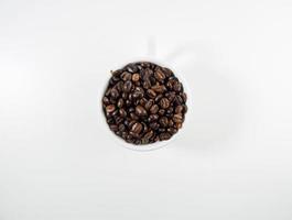rostad arabica kaffe bönor, redo till göra kaffe den där människor tycka om till dryck. placerad i en vit kaffe kopp på de bakgrund. utseende skön och aptitlig. dryck. foto