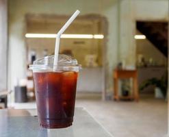 iced svart kaffe americano i en stor råna uppsättning på en speglad trä- tabell i de Kafé. uppfriskande dryck och vakna upp i de morgon- av de dag foto