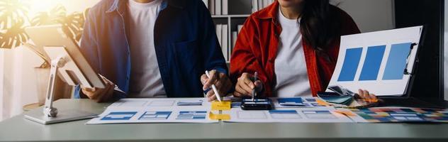 stänga upp ux utvecklare och ui designer brainstorming handla om mobil app gränssnitt trådmodell design på tabell med kund kortfattat och Färg koda på modern office.creative digital utveckling byrå foto