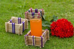 bambu pinnar glas hållare med en glas av orange juice på gräs bakgrund. foto