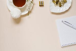 arbete skrivbord av en modern kvinna, Hem kontor. anteckningsblock, te, vår äpple blommor på en ljus tabell. minimal företag begrepp, platt lägga, plats för text. foto