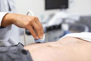 ultraljud diagnos av de mage på de abdominal hålighet av en man i de klinik, närbild se. de läkare kör ett ultraljud sensor över de patientens manlig buk. diagnostik av inre organ. foto