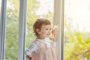 liten flicka stående på fönster tröskel foto