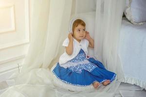 söt liten flicka spelar i ljus vit sovrum foto