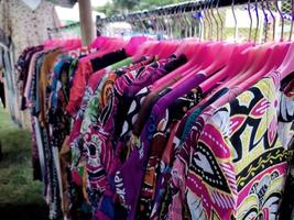 färgrik kvinnors batik trasa hängande på en galge i en traditionell marknadsföra. foto