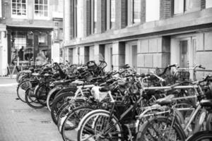 en svartvitt fotografera av cyklar parkerad i de Centrum av amsterdam foto